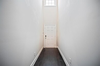 Doorway to outside featuring baseboards, dark wood-style floors, and a towering ceiling