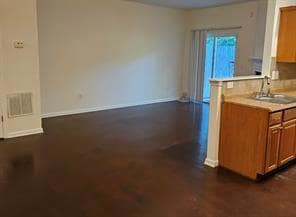 Kitchen featuring light countertops, brown cabinets, a peninsula, and dark wood-style flooring