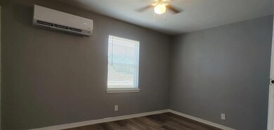 Empty room with dark hardwood / wood-style floors, ceiling fan, and a wall unit AC