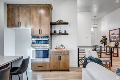 Kitchen with open shelves, light wood-style floors, stainless steel double oven, brown cabinets, and modern cabinets