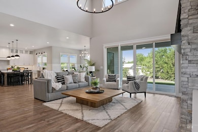 Living room with a chandelier, wood finished floors, a towering ceiling, and recessed lighting