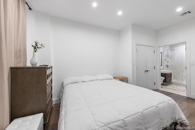 Bedroom featuring dark wood-type flooring, a closet, recessed lighting, and ensuite bathroom