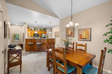 Dining room featuring light colored carpet, vaulted ceiling, a chandelier, and recessed lighting