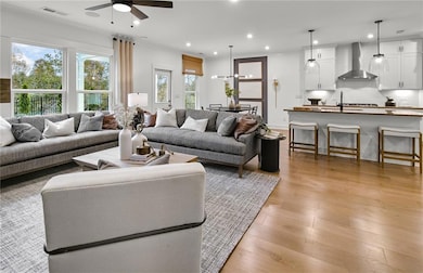 Living room with a ceiling fan, light wood-style floors, and recessed lighting