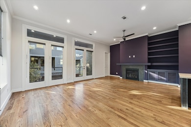 Spacious and inviting, this open-concept living room is designed for both comfort and style. Gleaming hardwood floors flow throughout, while a wall of French doors fills the space with natural light and offers easy access to the balcony. A cozy fireplace and custom built-ins create the perfect setting for relaxing evenings or hosting friends.