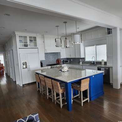 Kitchen with healthy amount of natural light, a kitchen breakfast bar, and white cabinetry