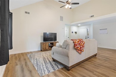 Living area with light wood-style flooring, high vaulted ceiling, and ceiling fan