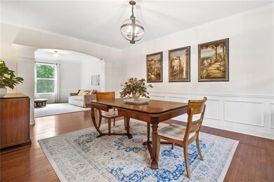 Dining area with decorative columns, arched walkways, hardwood / wood-style floors, crown molding, and a wainscoted wall