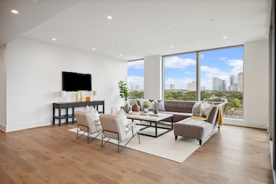 Floor-to-ceiling windows showcase panoramic views of the city. Photos are of a similar unit with the same floor plan