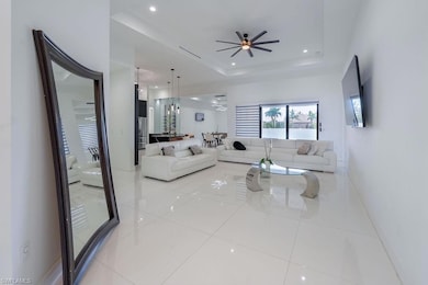Living area with a ceiling fan, recessed lighting, a tray ceiling, and light tile patterned floors