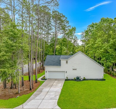 View of home's exterior featuring concrete driveway, a lawn, a shingled roof, and view of scattered trees
