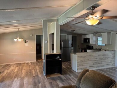 Kitchen with black appliances, white cabinetry, wood finished floors, and a chandelier