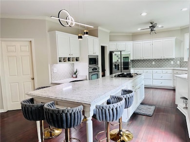Kitchen with a large island, white cabinetry, ornamental molding, and stainless steel appliances