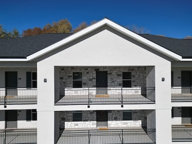 View of property exterior with stone siding, stucco siding, a balcony, and roof with shingles