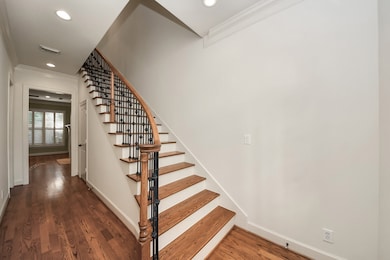 Inviting entryway featuring a beautiful wooden staircase with elegant wrought iron railing.