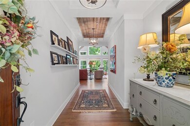 Hall with a chandelier, dark wood-type flooring, baseboards, and wooden ceiling