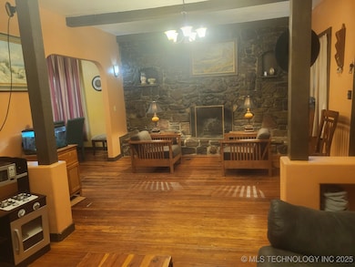 Den with stone wall and woodburning fireplace.