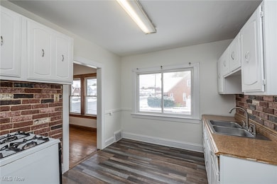Kitchen with white cabinetry, tasteful backsplash, dark wood-style flooring, and white gas range oven