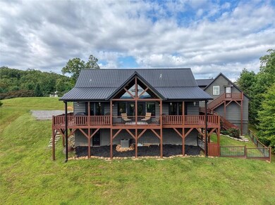 Rear view of house with a deck, a yard, and a metal roof