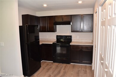 Kitchen with black appliances, dark brown cabinets, and light hardwood / wood-style floors