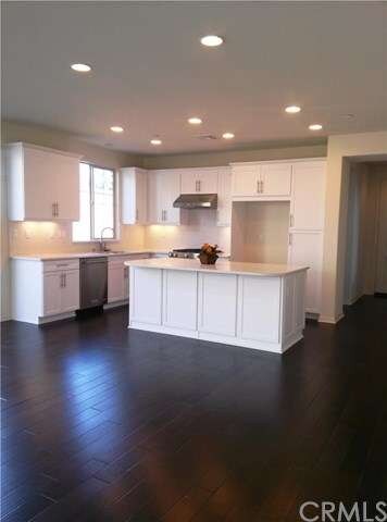 Bright kitchen with rich wood flooring, stainless 