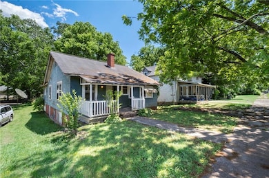 View of front of home with a porch, a chimney, a front yard, and a sunroom