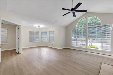 Unfurnished living room with a ceiling fan, light wood-type flooring, and high vaulted ceiling
