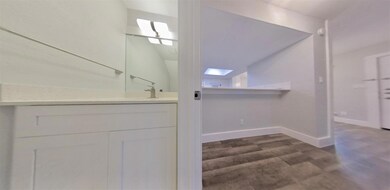 Bathroom featuring a skylight, vanity, and dark wood-style flooring