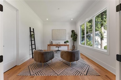 Office with light wood finished floors, crown molding, and recessed lighting