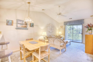 Living room with light colored carpet, vaulted ceiling, and ceiling fan with notable chandelier