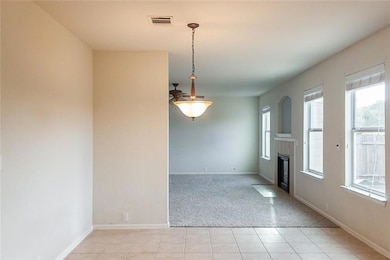 Unfurnished room with light tile patterned floors, light colored carpet, and a fireplace with flush hearth
