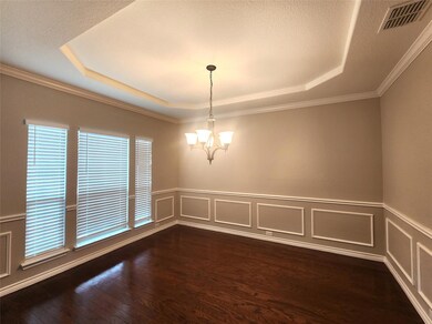 Empty room with dark hardwood / wood-style flooring, a textured ceiling, a tray ceiling, ornamental molding, and a notable chandelier