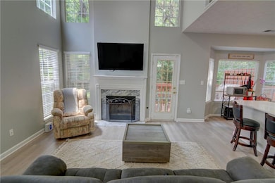 Living room featuring wood finished floors, a fireplace, baseboards, and a high ceiling