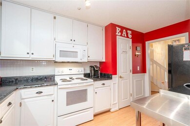 Kitchen featuring white appliances, white cabinetry, backsplash, light wood-style floors, and dark countertops