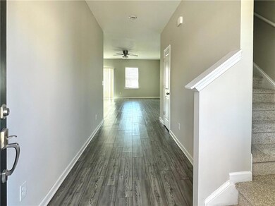 Hallway featuring dark wood finished floors, baseboards, and stairs