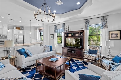 Living area with ornamental molding, a raised ceiling, a chandelier, recessed lighting, and wood finished floors