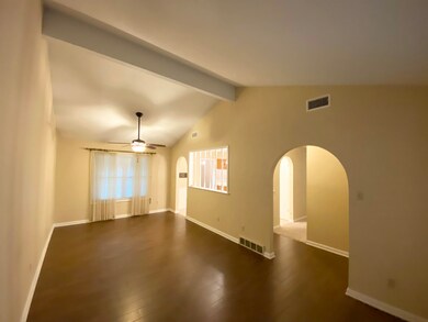 Living room/Dining room featuring ceiling fan, dark hardwood / wood-style floors, and vaulted ceiling with beams