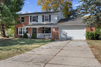 Traditional-style home featuring covered porch, brick siding, driveway, and a front yard