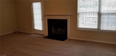The living room includes a wood burning fireplace, double windows for great light, and a rear French door that leads to the fenced patio area and storage room.
