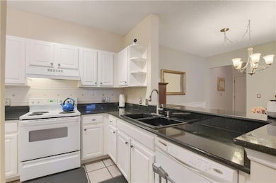 Kitchen with white appliances, backsplash, open shelves, under cabinet range hood, and white cabinetry