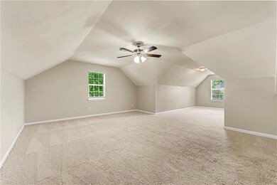 Additional living space featuring light colored carpet, lofted ceiling, plenty of natural light, and a ceiling fan