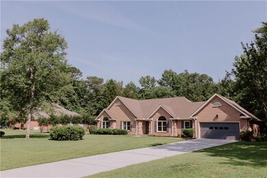 Ranch-style home featuring brick siding, a front yard, a garage, and concrete driveway