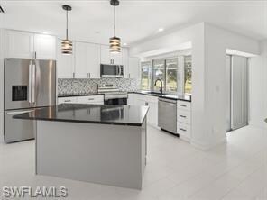 Kitchen with decorative light fixtures, white cabi