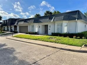 View of front of house featuring a garage, driveway, and mansard roof