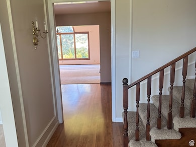 Hall with ornamental molding, stairs, and wood finished floors