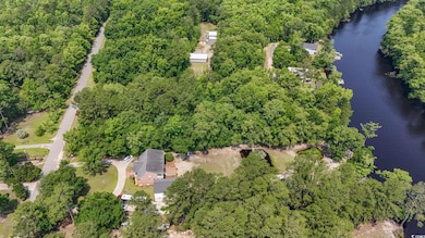 Aerial view of property's location featuring a large body of water and a forest