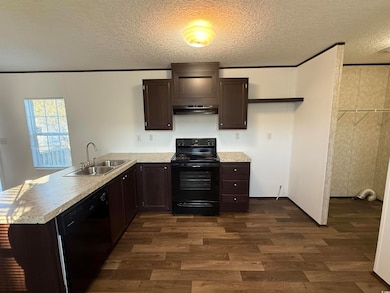 Kitchen with dark brown cabinetry, black appliances, a textured ceiling, dark wood finished floors, and light countertops