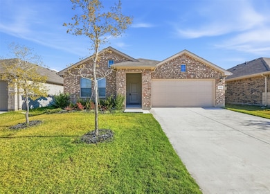 Ranch-style house featuring a front yard, driveway, brick siding, and a garage