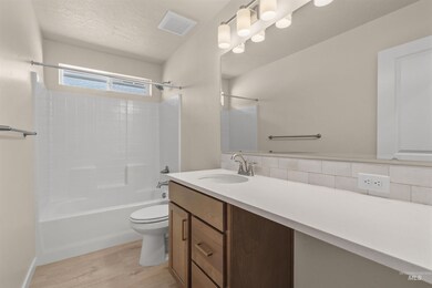 Bathroom with shower / tub combination, vanity, tasteful backsplash, light wood-style flooring, and a textured ceiling
