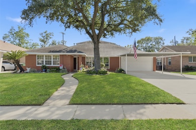 This charming single-story brick home features a well-maintained front yard with a large tree, a curved walkway leading to the entrance, and a spacious driveway with a carport. Its classic design is perfect for families seeking a cozy and inviting atmosphere.
